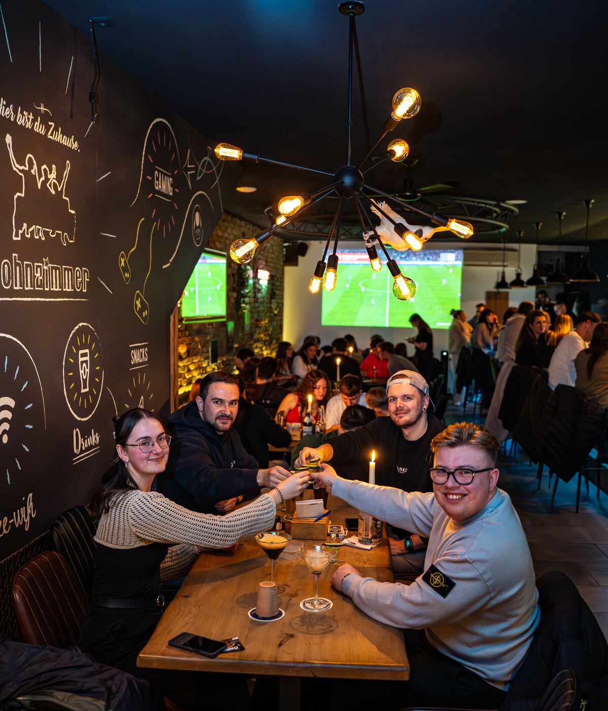 Gruppe stößt vor der Großleinwand an